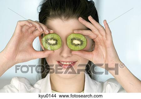 Portrait of a young smiling woman covering her eyes with 2 halves of kiwi fruit View Large Photo Image Picture - Portrait of a young smiling woman covering her eyes with 2 halves of kiwi fruit. Fotosearch