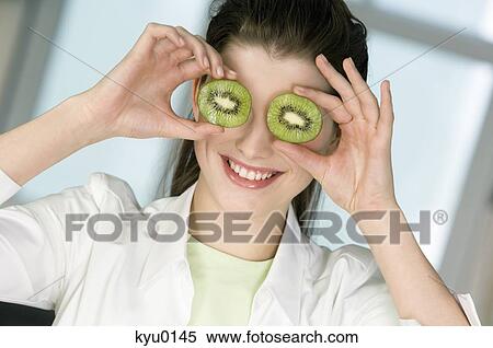 Portrait of a young smiling woman covering her eyes with 2 halves of kiwi fruit View Large Photo Image Stock Photography - Portrait of a young smiling woman covering her eyes with 2 halves of kiwi fruit. Fotosearch