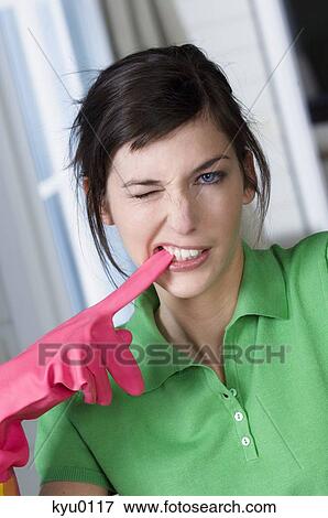 Stock Photo - Portrait of a young woman biting rubber glove. Fotosearch