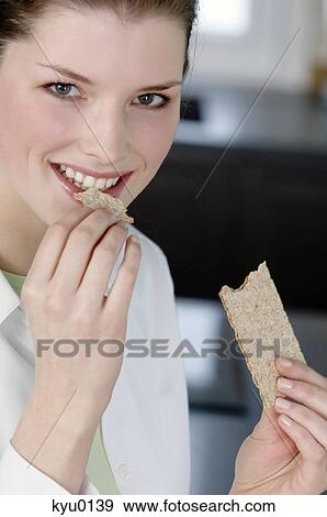 Portrait of a young woman eating a diet biscuit View Large Photo Image Stock Photo - Portrait of a young woman eating a diet biscuit. Fotosearch