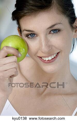 Portrait of a young woman eating an apple View Large Photo Image Stock Photo - Portrait of a young woman eating an apple. Fotosearch