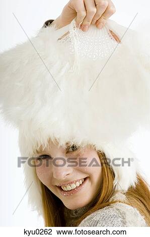 Stock Image - Portrait of a young woman holding a feather fan and smiling. Fotosearch