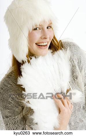 Stock Image - Portrait of a young woman holding a feather fan and smiling. Fotosearch