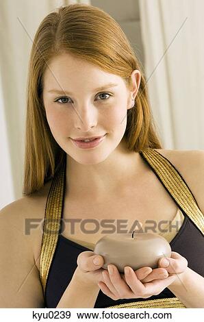 Stock Photo - Portrait of a young woman holding a burning candle and smiling. Fotosearch
