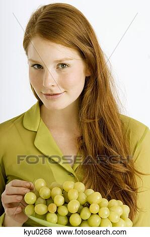 Portrait of a young woman holding a plate of grapes and smiling View Large Photo Image Stock Photo - Portrait of a young woman holding a plate of grapes and smiling. Fotosearch