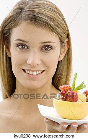 Stock Photo - Portrait of a young woman holding a bowl of fruit salad. Fotosearch