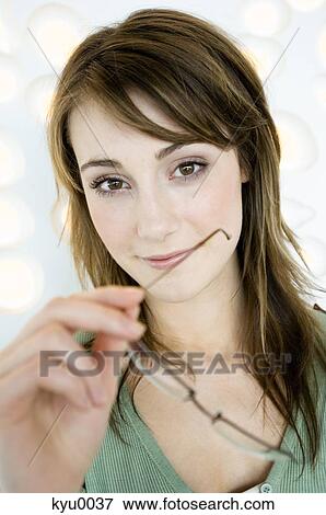 Stock Photo - Portrait of a young woman holding pair of glasses. Fotosearch