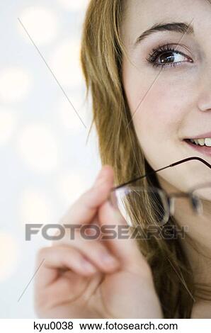 Stock Photo - Portrait of a young woman holding pair of glasses. Fotosearch