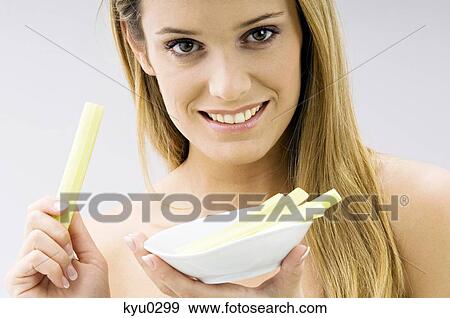 Portrait of a young woman holding celery sticks and smiling View Large Photo Image Stock Photo - Portrait of a young woman holding celery sticks and smiling. Fotosearch