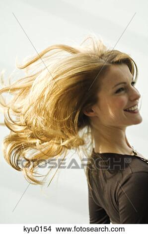 Picture - Portrait of a young woman smilng, blond hair, blurred motion. Fotosearch