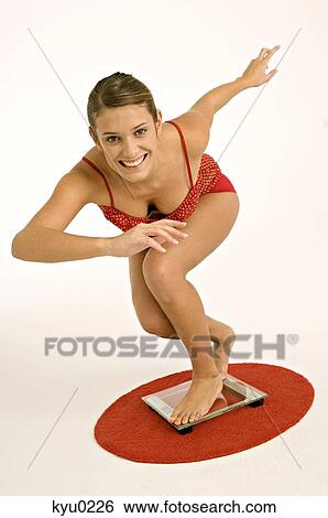Portrait of a young woman standing on a bathroom scale and smiling View Large Photo Image Stock Photograph - Portrait of a young woman standing on a bathroom scale and smiling. Fotosearch