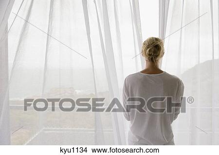 Rear view of a woman opening the curtain of balcony View Large Photo Image Picture - Rear view of a woman opening the curtain of balcony. Fotosearch