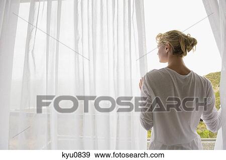 Rear view of a woman standing on balcony View Large Photo Image Stock Photo - Rear view of a woman standing on balcony. Fotosearch