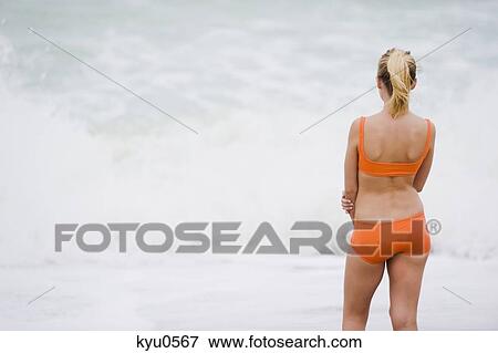 Rear view of a woman standing on the beach View Large Photo Image Stock Photo - Rear view of a woman standing on the beach. Fotosearch