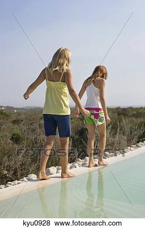 Rear view of two girls playing at the poolside View Large Photo Image Stock Photo - Rear view of two girls playing at the poolside. Fotosearch