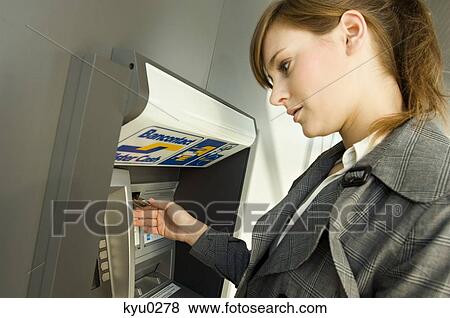 Stock Photo - Side profile of a businesswoman using an ATM. Fotosearch