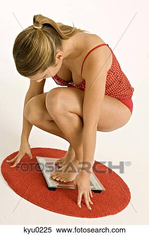 Side profile of a young woman crouching on a bathroom scale View Large Photo Image Stock Photography - Side profile of a young woman crouching on a bathroom scale. Fotosearch