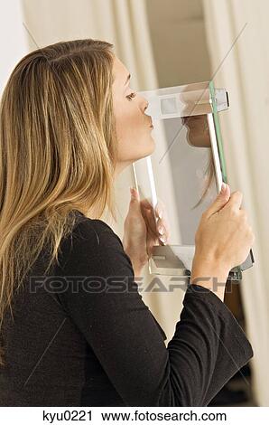 Side profile of a young woman kissing a weight scale View Large Photo Image Stock Image - Side profile of a young woman kissing a weight scale. Fotosearch