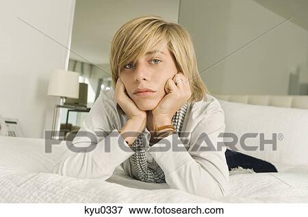Teenage boy lying on the bed and looking serious View Large Photo Image Stock Photo - Teenage boy lying on the bed and looking serious. Fotosearch
