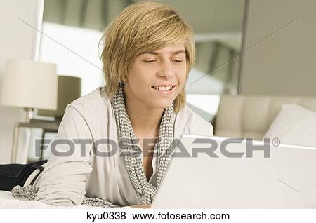 Stock Photo - Teenage boy working on a laptop and smiling. Fotosearch
