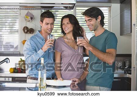 Three friends drinking wine in the kitchen View Large Photo Image Stock Photo - Three friends drinking wine in the kitchen. Fotosearch