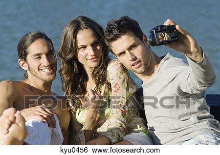 Three friends taking a picture of themselves with a digital camera View Large Photo Image Stock Photograph - Three friends taking a picture of themselves with a digital camera. Fotosearch