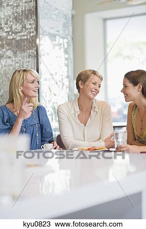 Stock Image - Three women sitting in a restaurant. Fotosearch