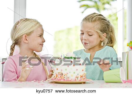 Stock Photo - Two girls eating birthday cake. Fotosearch
