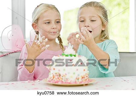 Stock Photo - Two girls eating birthday cake. Fotosearch