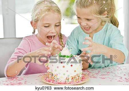 Stock Image - Two girls looking at a birthday cake. Fotosearch