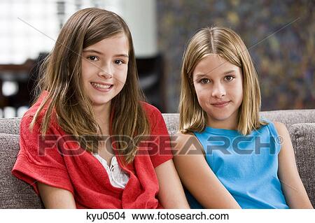 Two girls sitting on a couch View Large Photo Image Picture - Two girls sitting on a couch. Fotosearch