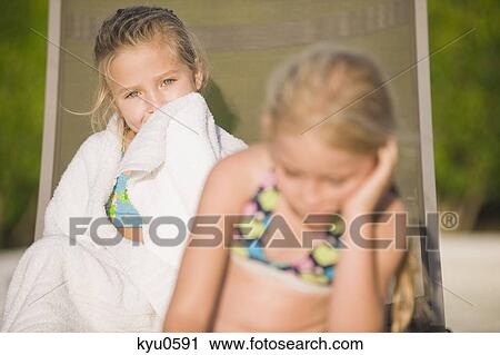 Two girls sitting on a lounge chair and ignoring each other View Large Photo Image Stock Image - Two girls sitting on a lounge chair and ignoring each other. Fotosearch
