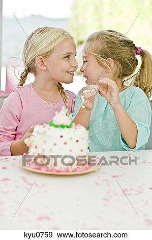 Two girls smiling in front of a birthday cake View Large Photo Image Stock Photo - Two girls smiling in front of a birthday cake. Fotosearch
