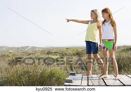 Two girls standing on a boardwalk View Large Photo Image Stock Photography - Two girls standing on a boardwalk. Fotosearch