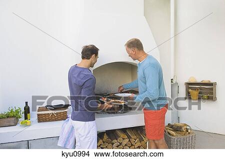 Two men cooking kebab at fireplace View Large Photo Image Picture - Two men cooking kebab at fireplace. Fotosearch
