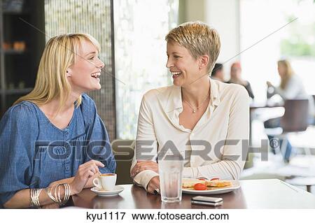 Two women sitting in a restaurant and smiling View Large Photo Image Stock Photo - Two women sitting in a restaurant and smiling. Fotosearch