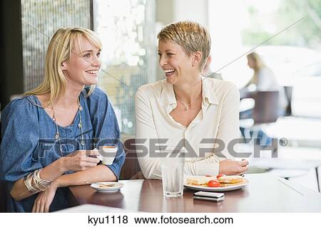 Two women sitting in a restaurant and smiling View Large Photo Image Stock Photo - Two women sitting in a restaurant and smiling. Fotosearch