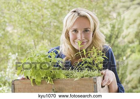 Stock Image - Woman carrying a crate of plants. Fotosearch
