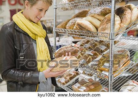 Stock Image - Woman choosing breads in a supermarket. Fotosearch