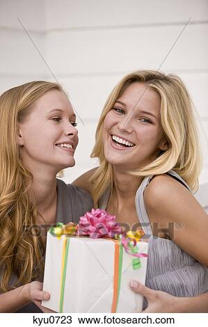 Woman giving a present to her friend View Large Photo Image Stock Image - Woman giving a present to her friend. Fotosearch