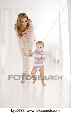 Woman helping her daughter to walk View Large Photo Image Stock Image - Woman helping her daughter to walk. Fotosearch