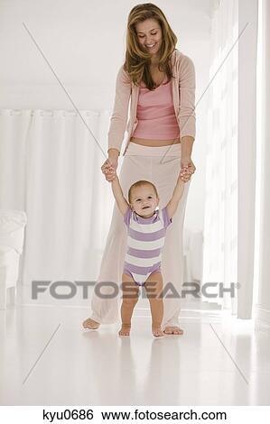 Woman helping her daughter to walk View Large Photo Image Stock Photograph - Woman helping her daughter to walk. Fotosearch