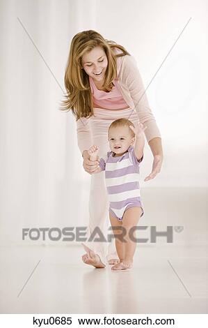 Stock Photography - Woman helping her daughter to walk. Fotosearch
