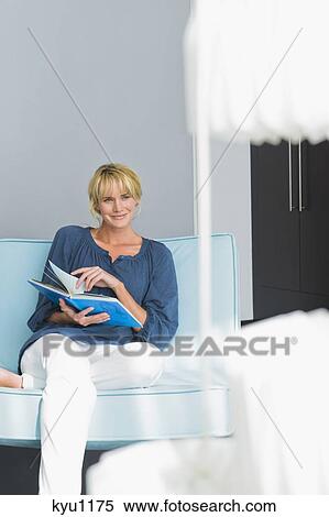 Woman holding a book on a couch View Large Photo Image Stock Photography - Woman holding a book on a couch. Fotosearch