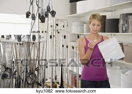 Woman holding a lampshade in a store View Large Photo Image Stock Image - Woman holding a lampshade in a store. Fotosearch