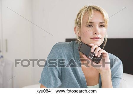 Woman holding a mobile phone and thinking View Large Photo Image Stock Image - Woman holding a mobile phone and thinking. Fotosearch