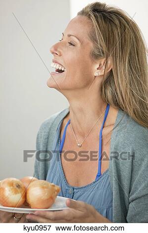 Stock Photo - Woman holding a plate of onions and laughing. Fotosearch