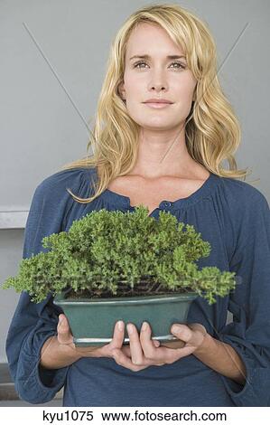 Stock Photography - Woman holding a potted plant. Fotosearch