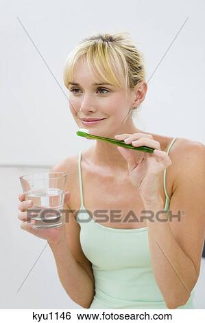 Woman holding a toothbrush with a glass of water View Large Photo Image Stock Photograph - Woman holding a toothbrush with a glass of water. Fotosearch