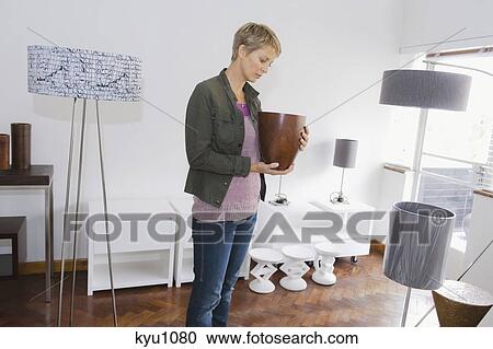 Woman holding a vase in a store View Large Photo Image Stock Image - Woman holding a vase in a store. Fotosearch